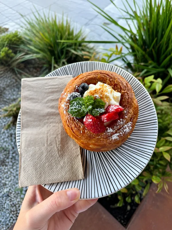 Berry-filled pastry topped with cream on a striped plate