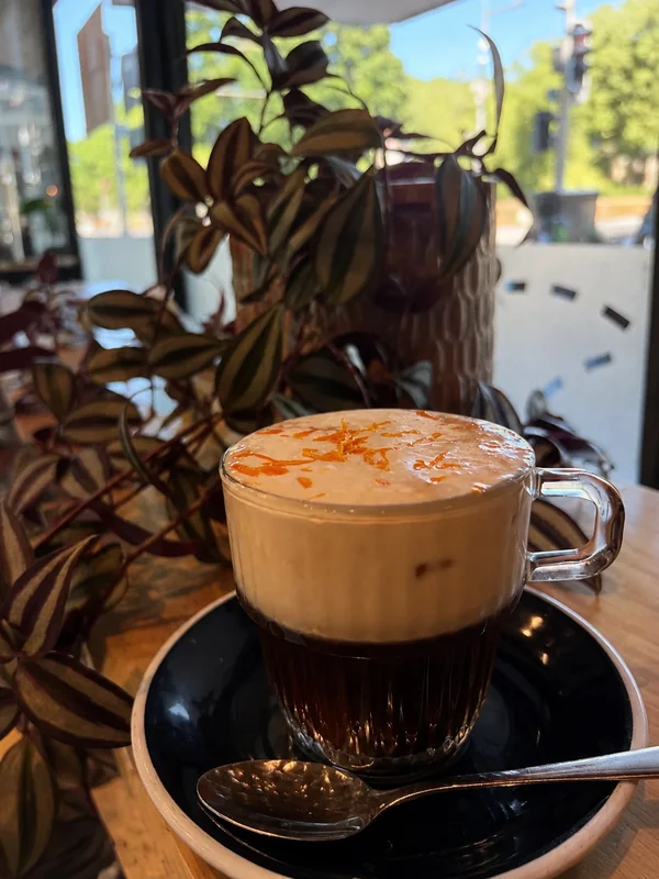 A frothy coffee in a black cup at Therapy Coffee