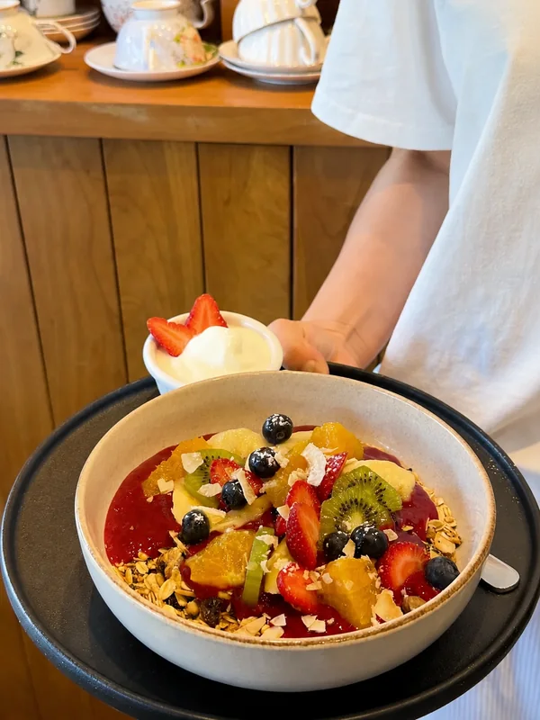 A fruit and granola bowl being served with yoghurt